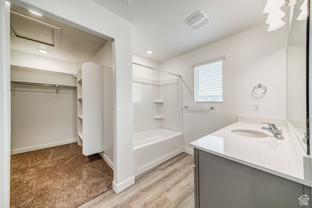 Bathroom with hardwood / wood-style floors, vanity, and bathing tub / shower combination