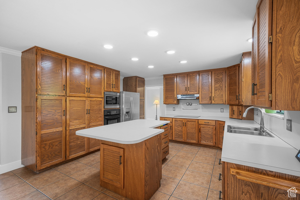 Kitchen with a center island, crown molding, black appliances, light tile floors, and sink