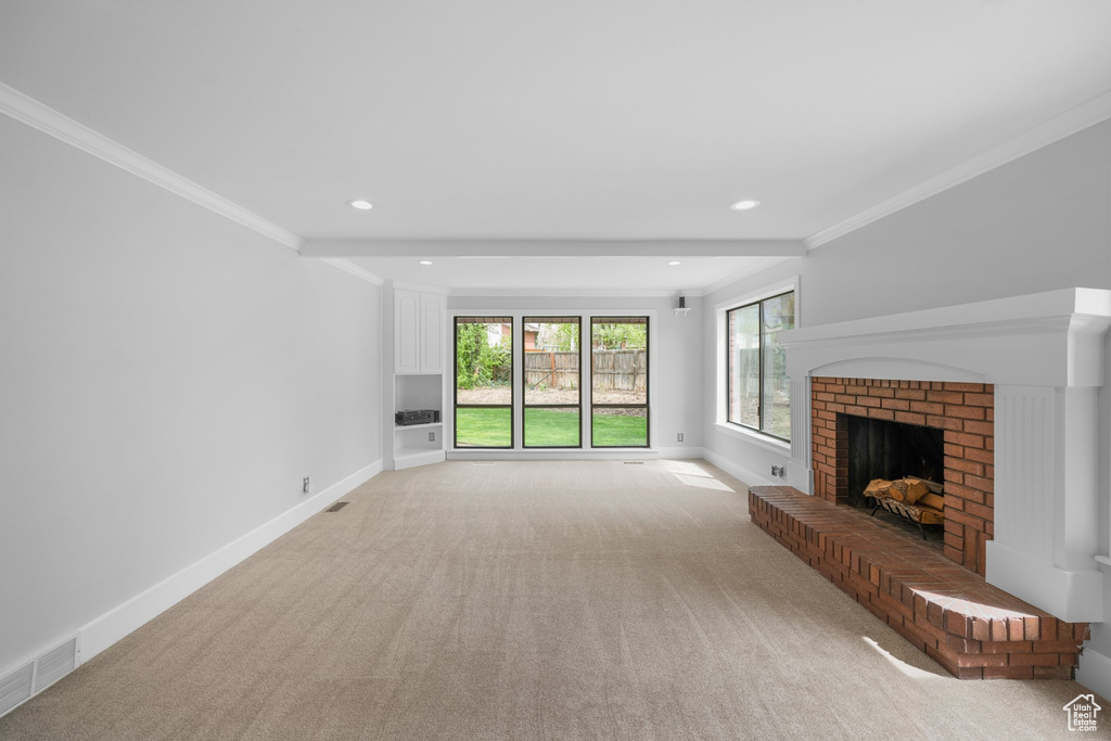 Unfurnished living room with crown molding, light colored carpet, and a brick fireplace