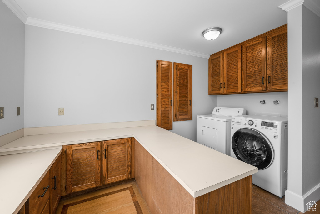 Laundry room with ornamental molding, cabinets, and separate washer and dryer