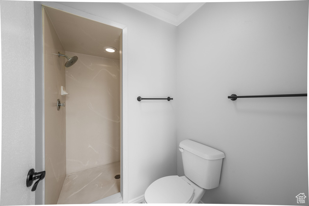 Bathroom with walk in shower, crown molding, and toilet