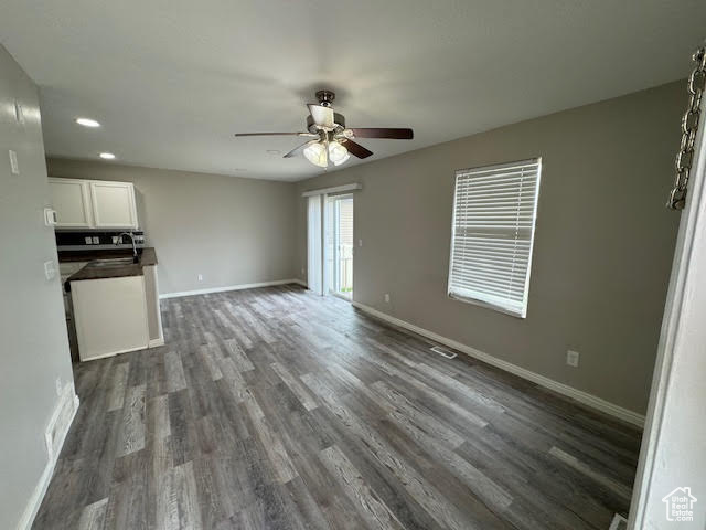 Unfurnished living room featuring sink, ceiling fan, and dark hardwood / wood-style flooring