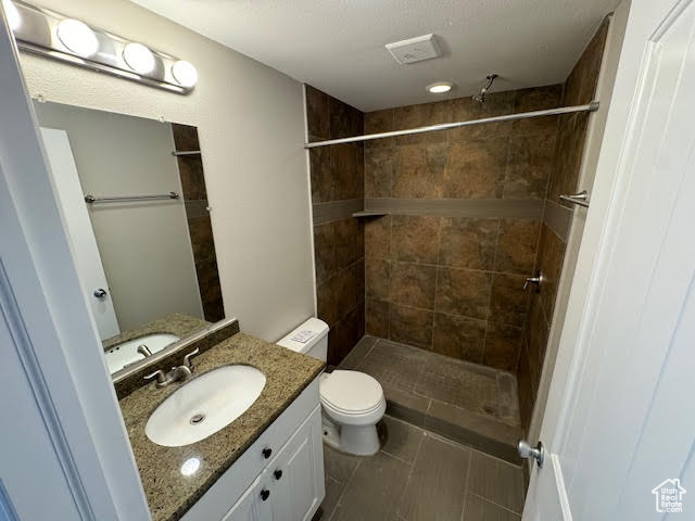 Bathroom with oversized vanity, tile floors, toilet, and a tile shower