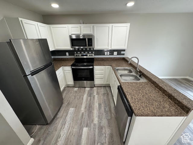 Kitchen with appliances with stainless steel finishes, sink, backsplash, and light wood-type flooring