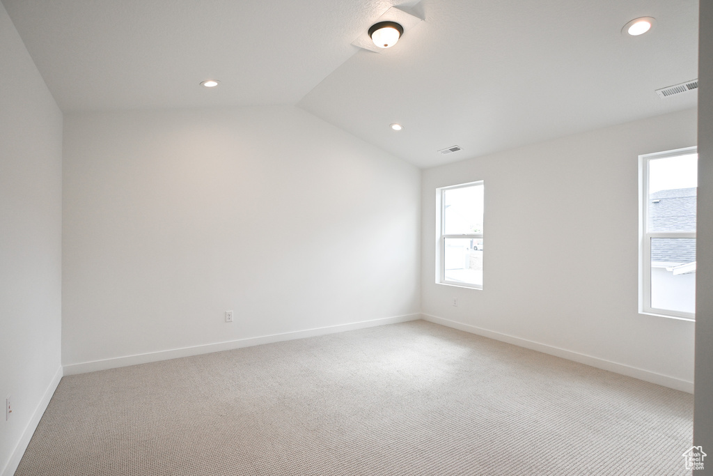 Unfurnished room featuring vaulted ceiling and carpet flooring