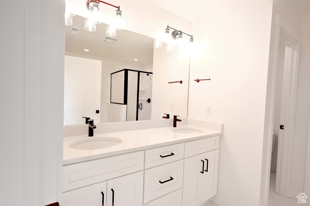 Bathroom with double sink, oversized vanity, and a shower with door