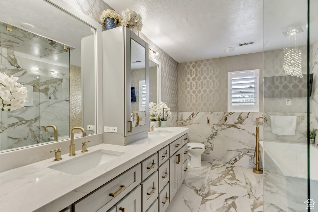 Bathroom featuring tile walls, large vanity, dual sinks, tile floors, and toilet