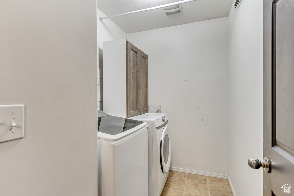 Laundry room with light tile floors and washing machine and clothes dryer