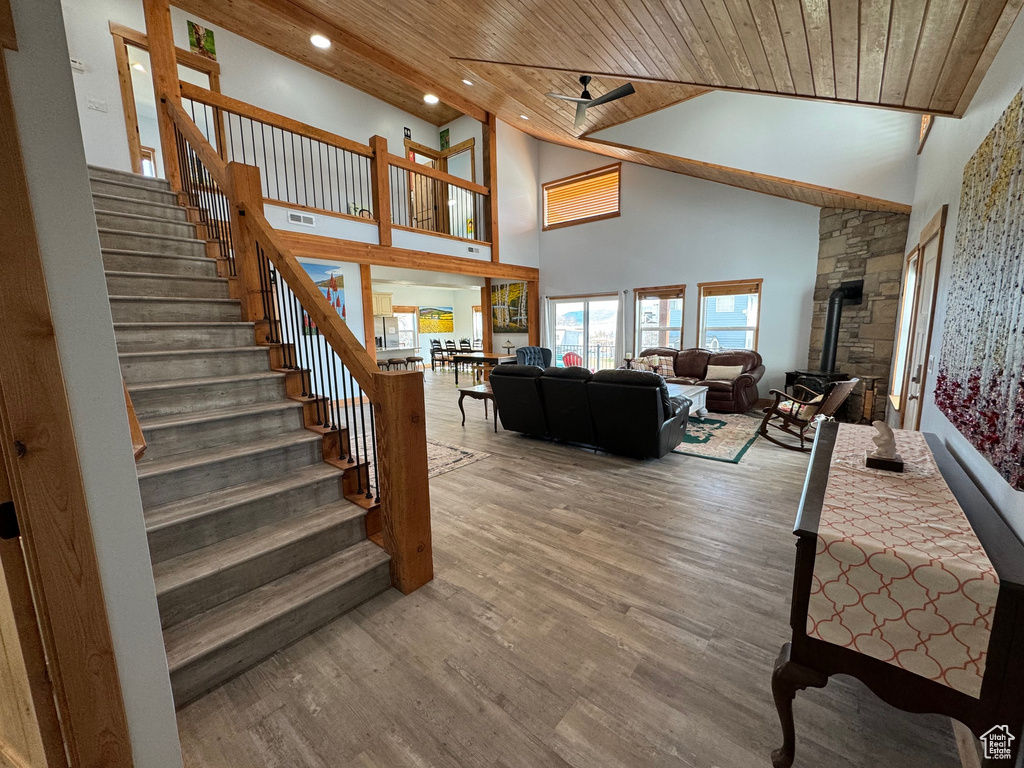 Staircase with hardwood / wood-style floors, wooden ceiling, a wood stove, and high vaulted ceiling