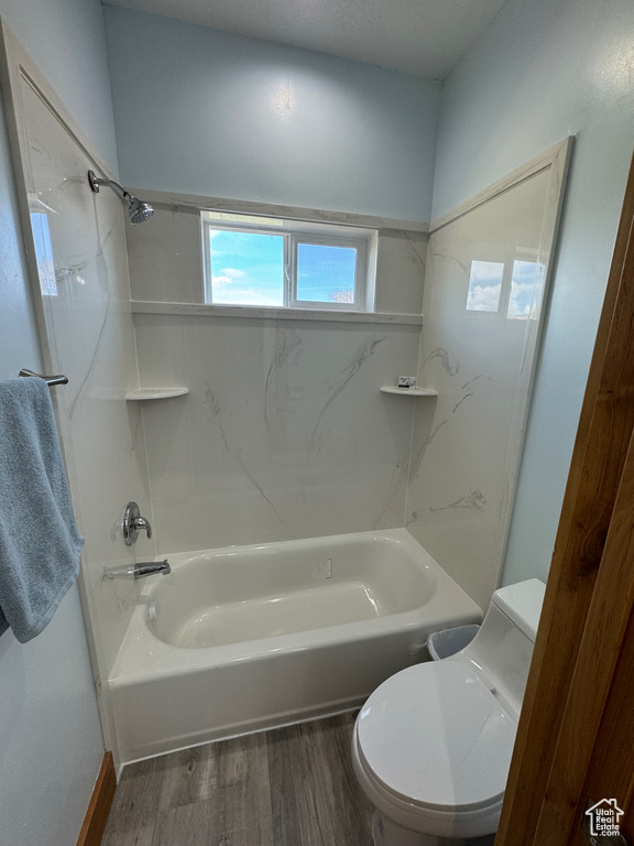 Bathroom with wood-type flooring, shower / bathing tub combination, and toilet