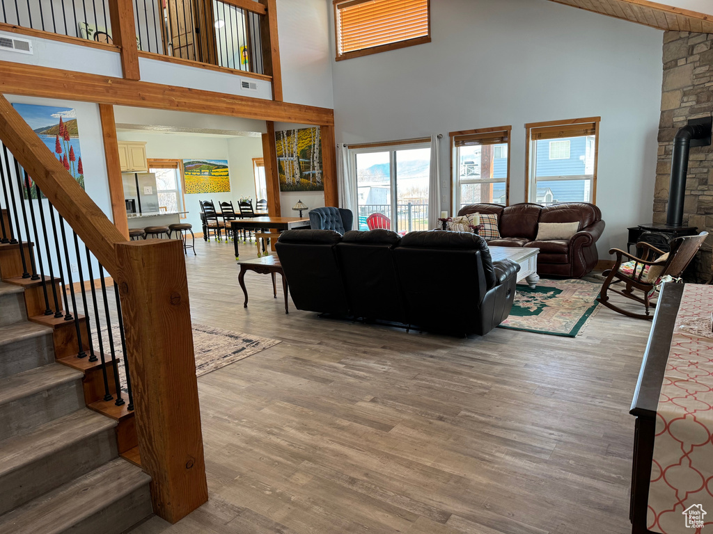Living room featuring a high ceiling, hardwood / wood-style flooring, and a wood stove