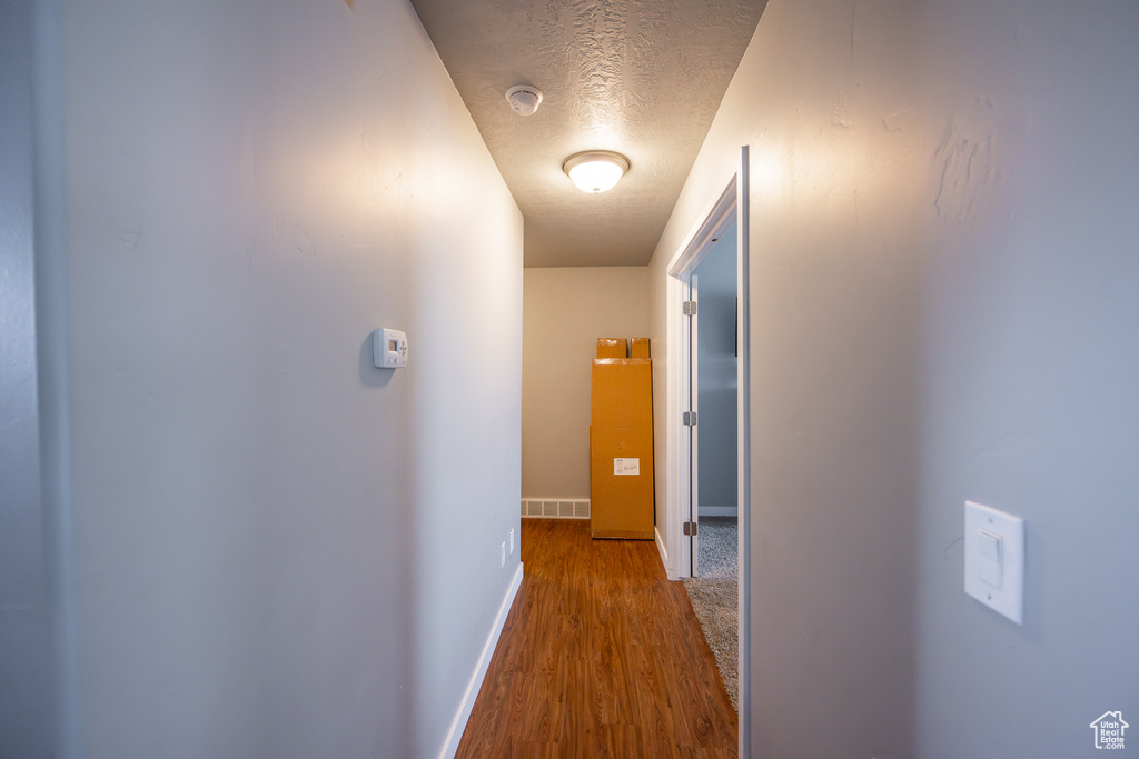 Hall featuring a textured ceiling and hardwood / wood-style flooring