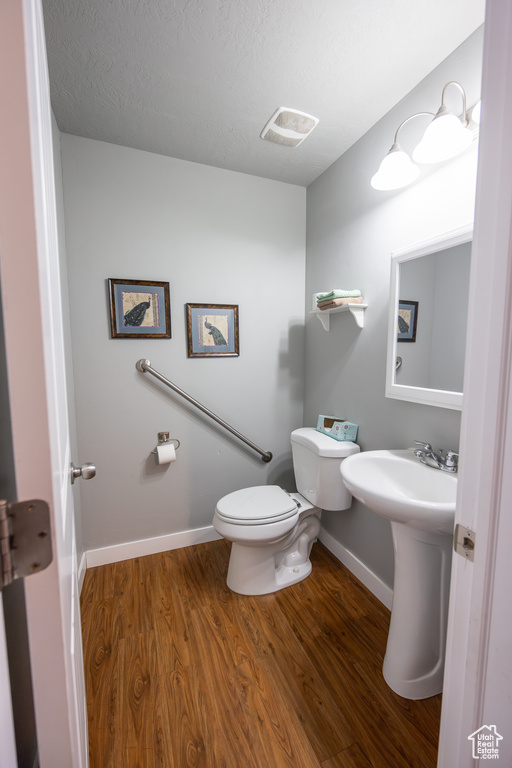 Bathroom with a textured ceiling, toilet, and hardwood / wood-style floors