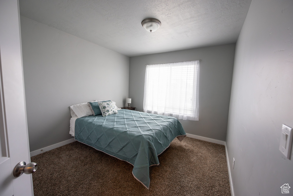 Bedroom with dark carpet and a textured ceiling