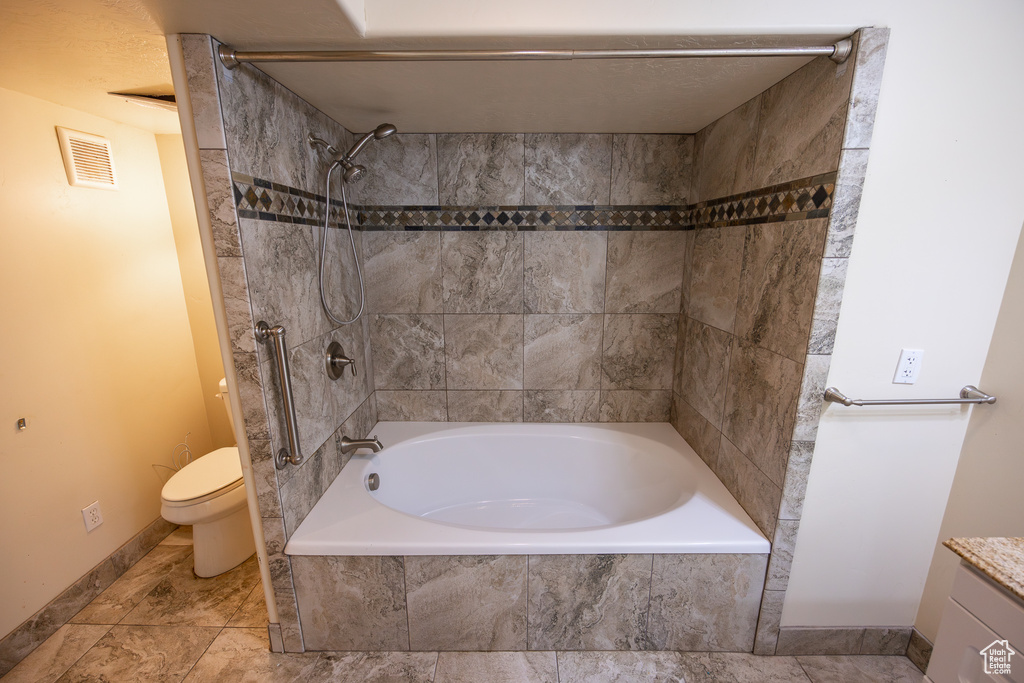 Full bathroom featuring tiled shower / bath combo, vanity, toilet, and tile flooring