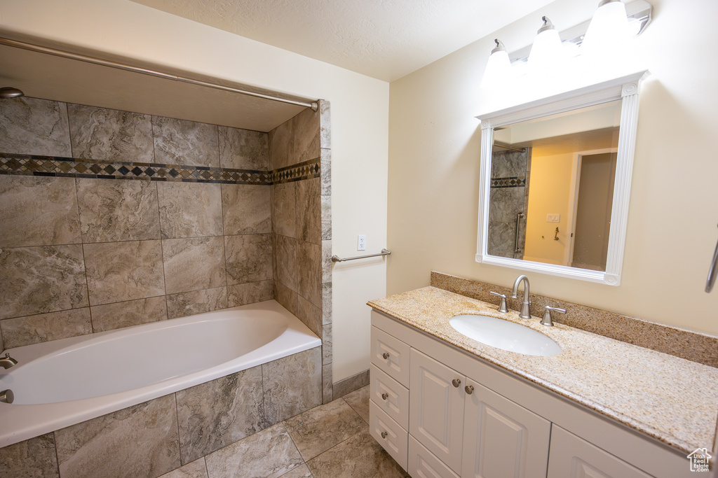 Bathroom with tiled shower / bath, tile floors, and vanity