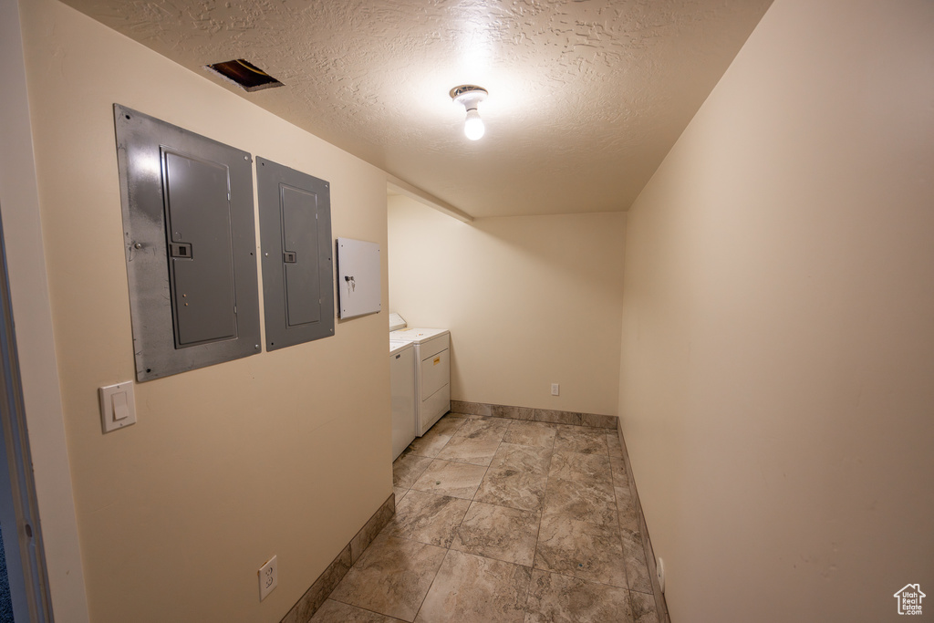 Hall featuring a textured ceiling, separate washer and dryer, and light tile flooring