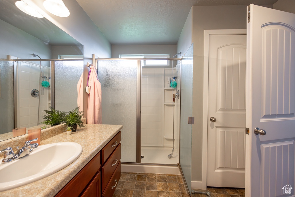 Bathroom with tile flooring, large vanity, and a shower with shower door