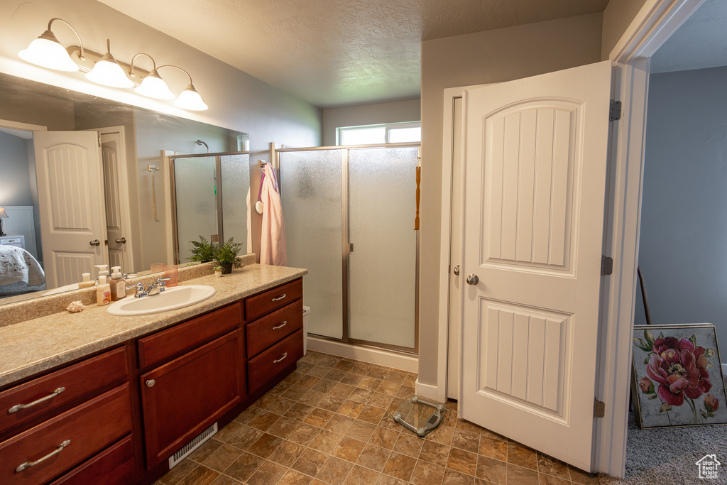 Bathroom featuring walk in shower, vanity with extensive cabinet space, and tile floors