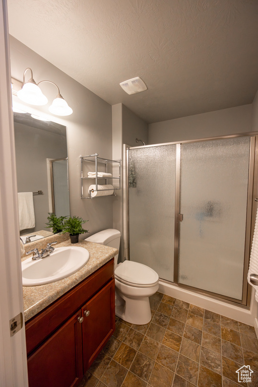 Bathroom with a shower with shower door, toilet, tile floors, and vanity