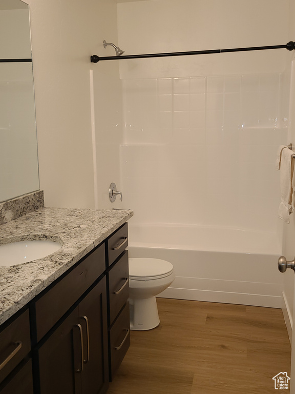 Full bathroom featuring oversized vanity, hardwood / wood-style floors, shower / tub combination, and toilet
