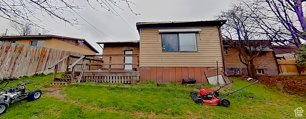 Rear view of property featuring a wooden deck and a lawn