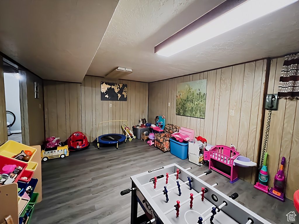 Recreation room with wooden walls and hardwood / wood-style floors