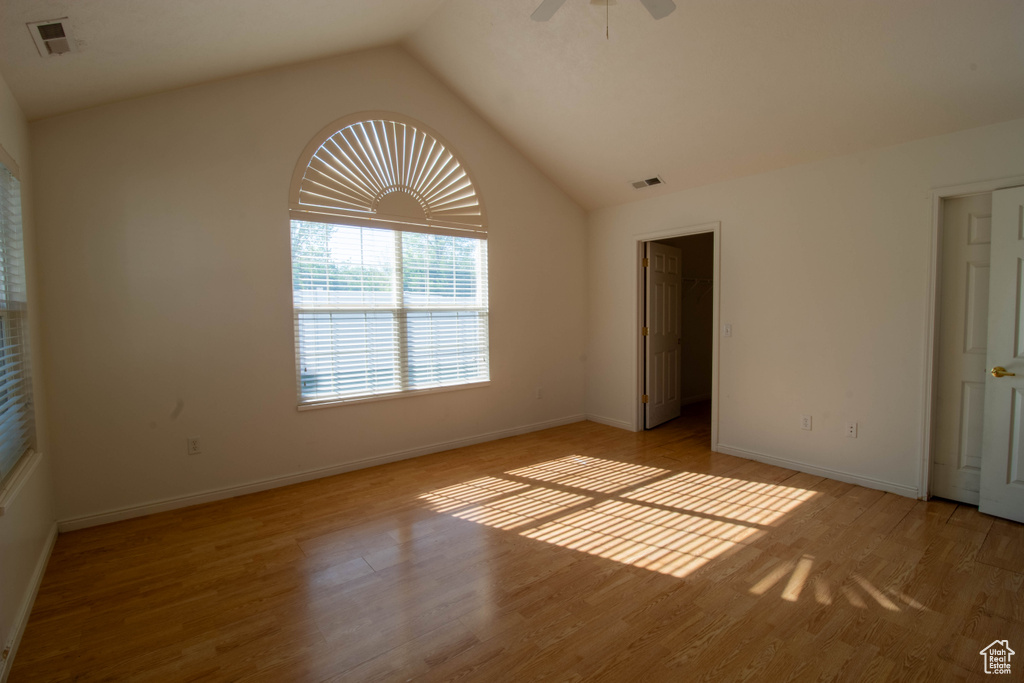 Unfurnished bedroom with hardwood / wood-style floors, lofted ceiling, ceiling fan, and a spacious closet
