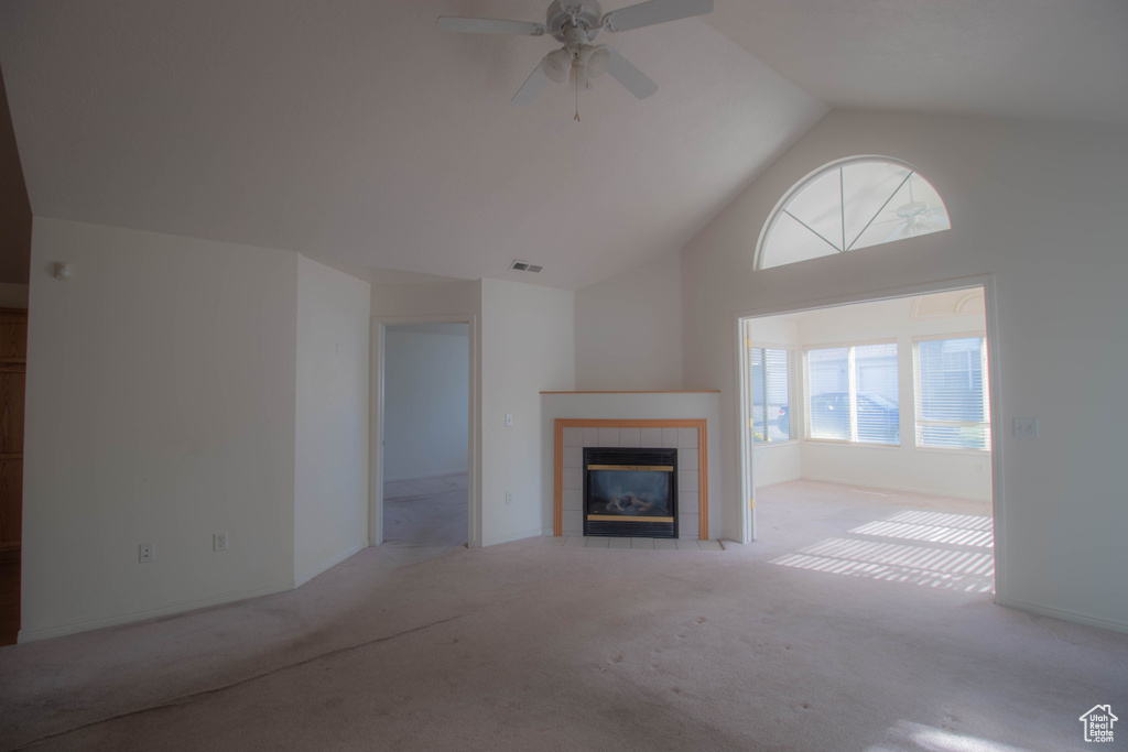 Unfurnished living room with high vaulted ceiling, light colored carpet, ceiling fan, and a fireplace