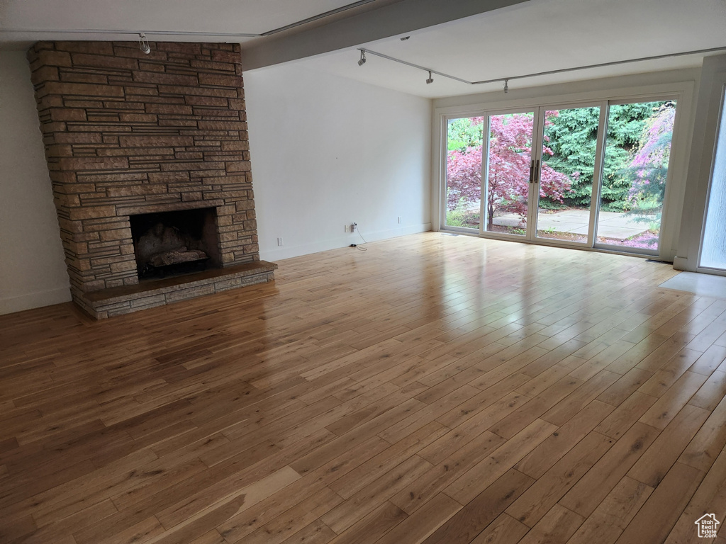 Unfurnished living room with rail lighting, a fireplace, and hardwood / wood-style flooring