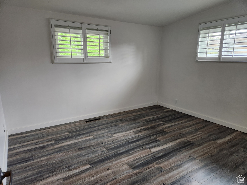 Spare room with dark hardwood / wood-style floors and lofted ceiling