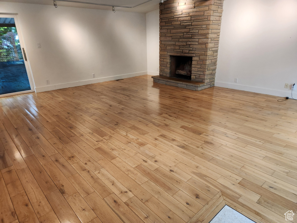 Unfurnished living room with light hardwood / wood-style floors and a stone fireplace