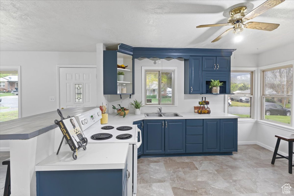 Kitchen featuring white electric stove, ceiling fan, blue cabinetry, and light tile floors