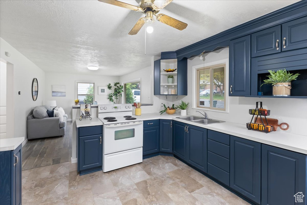 Kitchen featuring sink, light tile floors, blue cabinetry, and white electric range