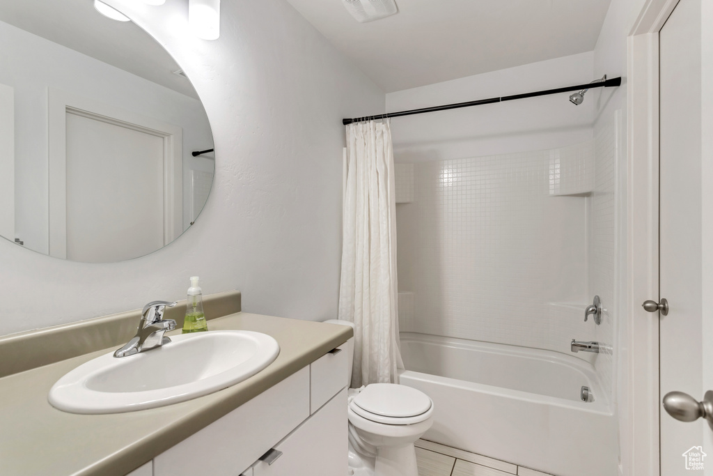 Full bathroom with oversized vanity, shower / bath combo, tile floors, and toilet