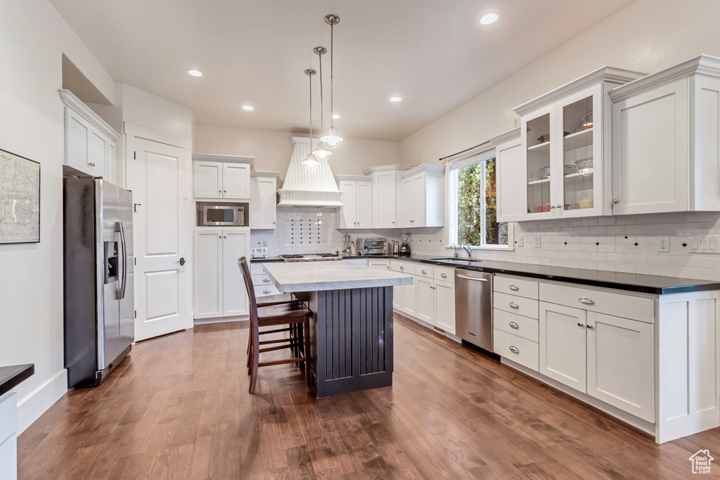 Kitchen featuring a kitchen island, stainless steel appliances, dark hardwood / wood-style flooring, and custom exhaust hood