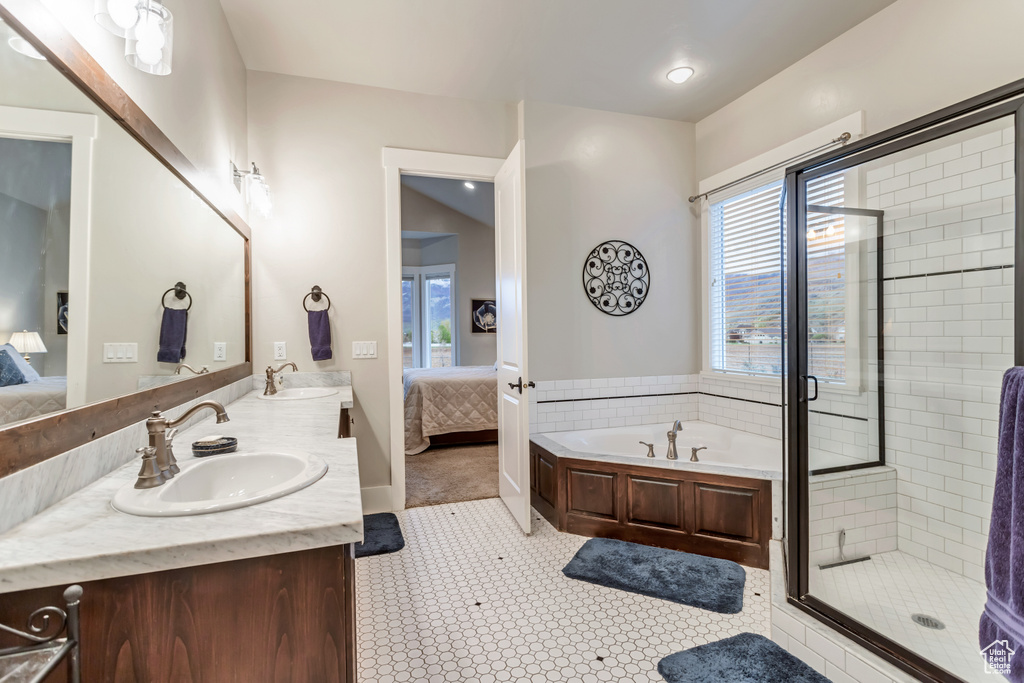 Bathroom with a wealth of natural light, separate shower and tub, large vanity, and dual sinks
