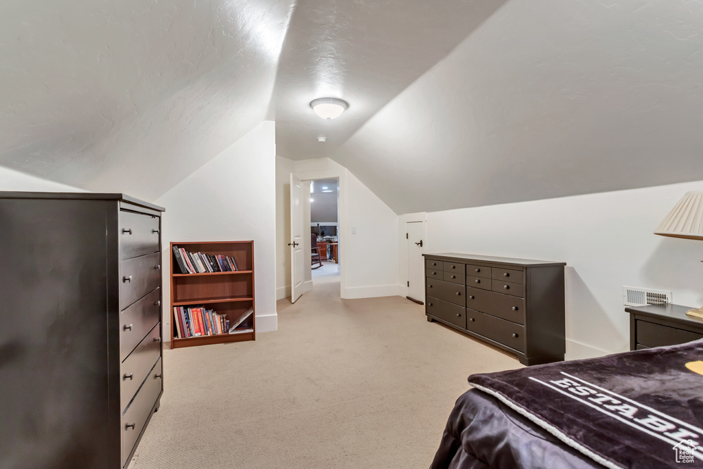 Bedroom with light colored carpet and lofted ceiling