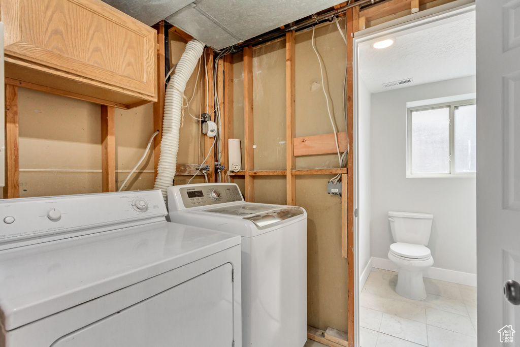 Washroom with tile floors, washer hookup, and washing machine and clothes dryer