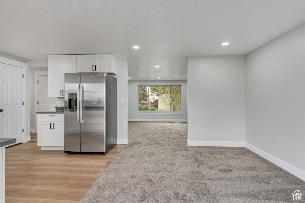 Kitchen featuring light hardwood / wood-style flooring, stainless steel fridge with ice dispenser, and white cabinetry