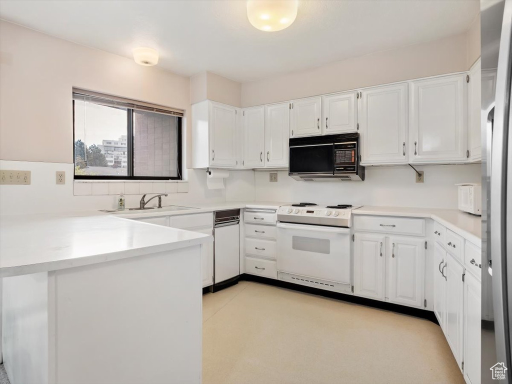 Kitchen with kitchen peninsula, white cabinets, white appliances, and sink