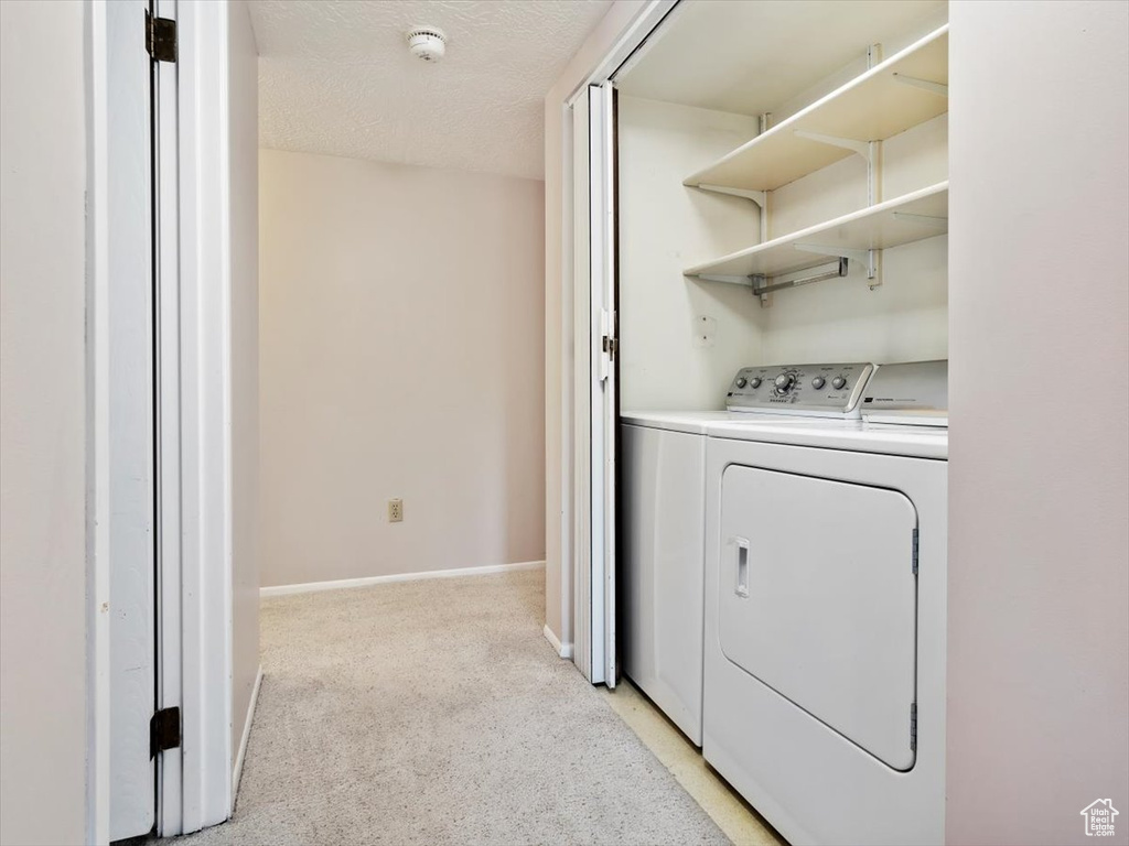 Laundry room featuring independent washer and dryer and a textured ceiling