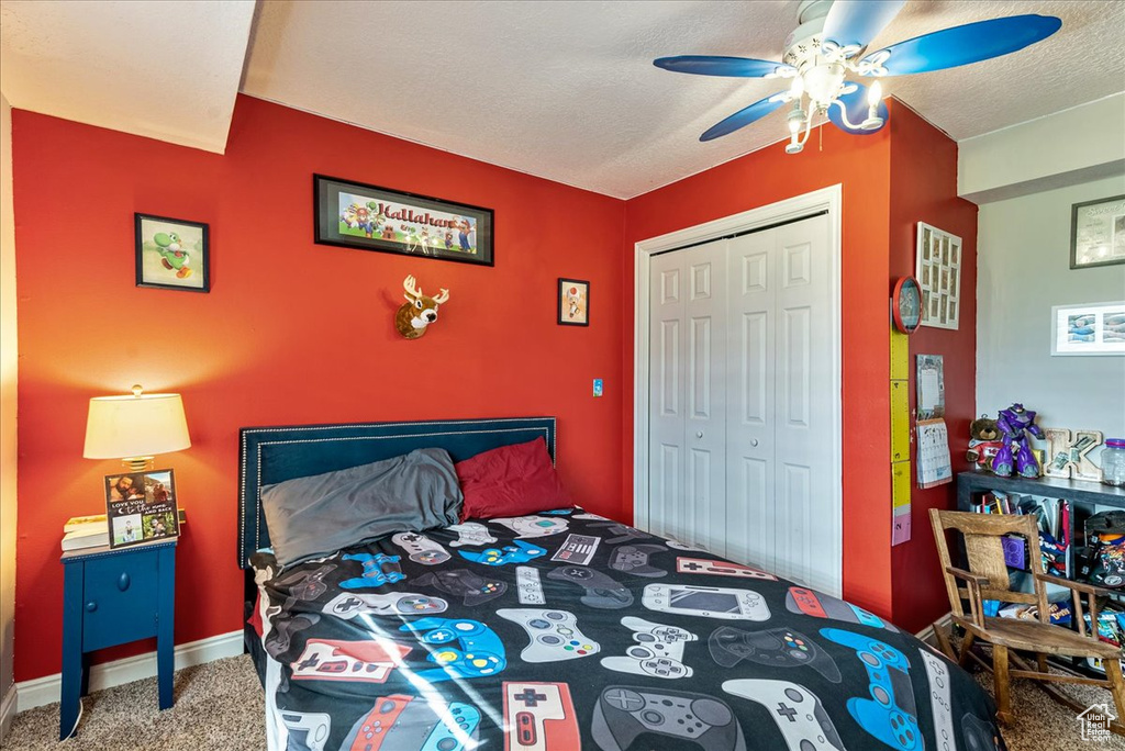 Bedroom featuring carpet, ceiling fan, a closet, and a textured ceiling