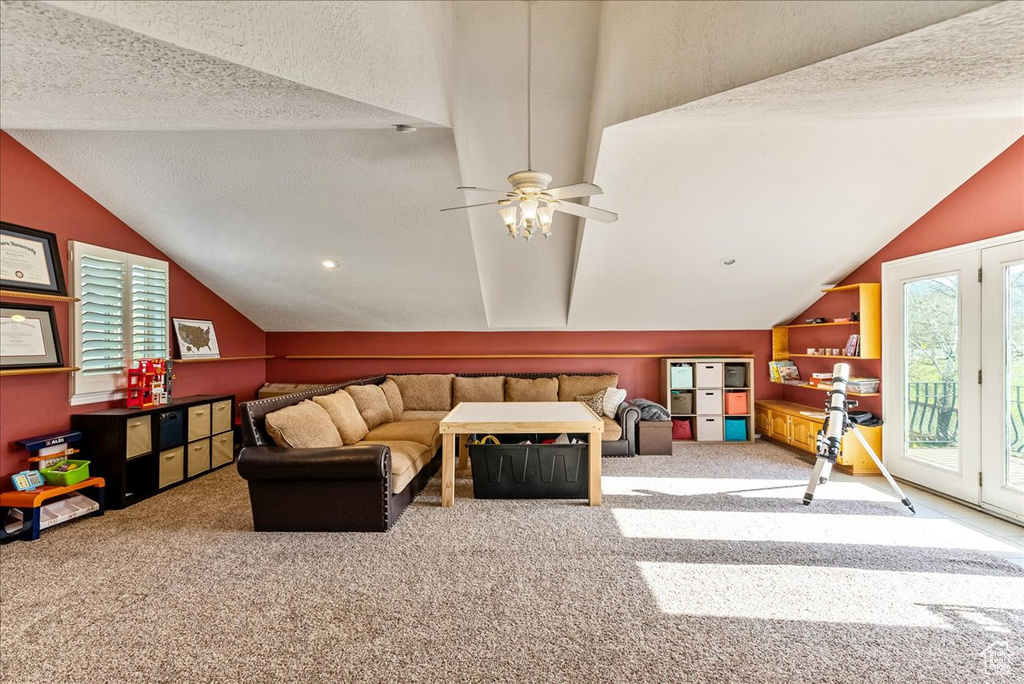 Living room featuring lofted ceiling, ceiling fan, and carpet