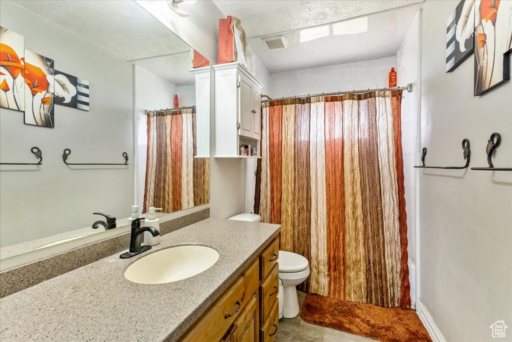 Bathroom featuring toilet, a textured ceiling, and large vanity