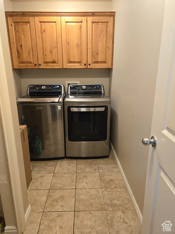 Laundry room with cabinets, light tile floors, hookup for a washing machine, and washer and clothes dryer