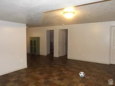 Empty room with dark tile flooring and a textured ceiling