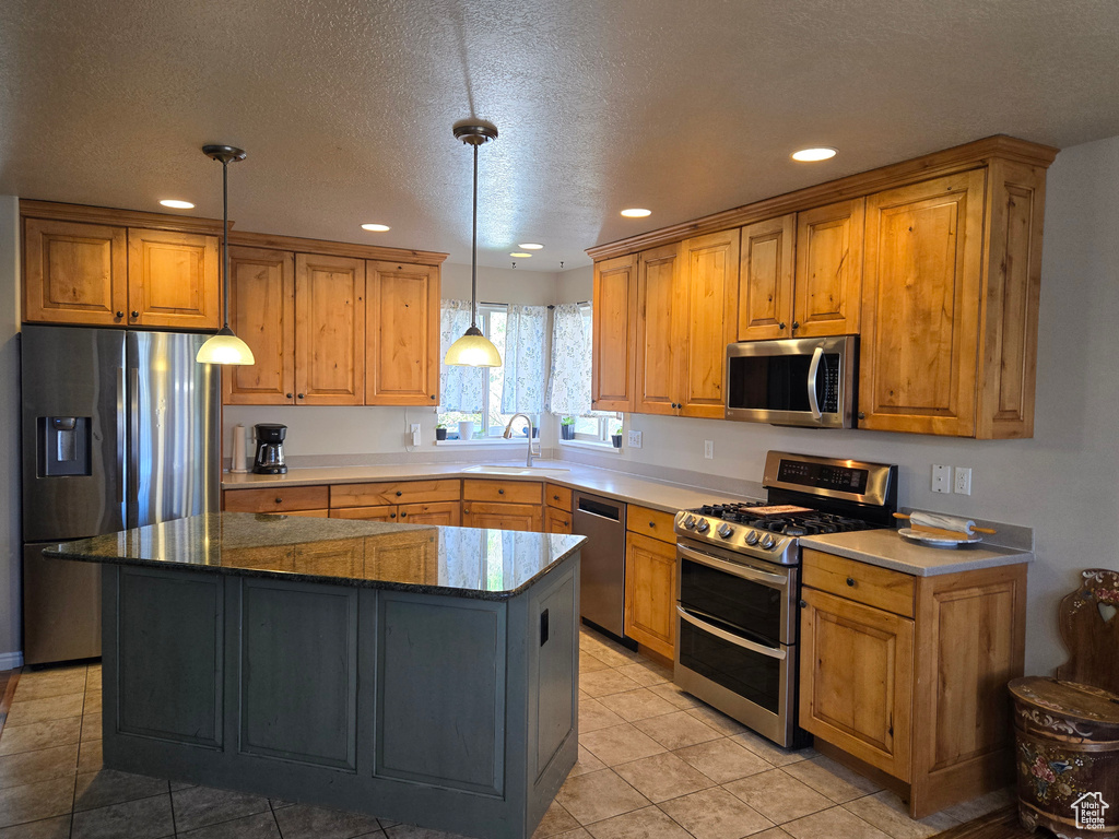 Kitchen with a kitchen island, pendant lighting, stainless steel appliances, and light tile floors