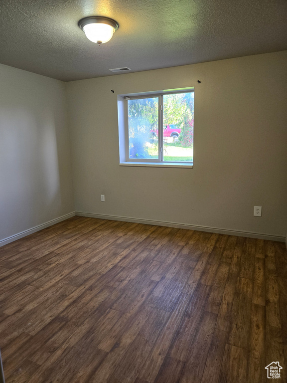 Unfurnished room featuring dark hardwood / wood-style flooring and a textured ceiling