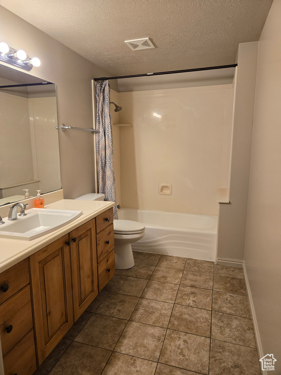 Full bathroom with shower / bath combo with shower curtain, tile floors, vanity, toilet, and a textured ceiling
